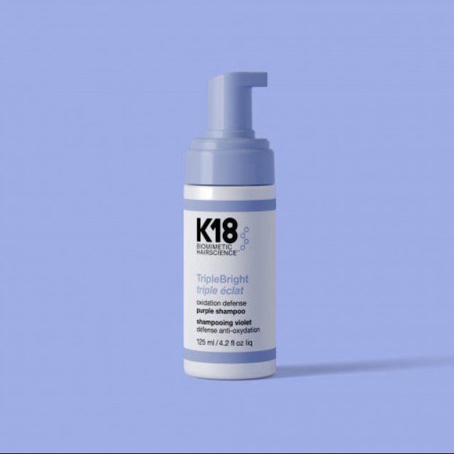 K18 hair product bottle on a light purple background