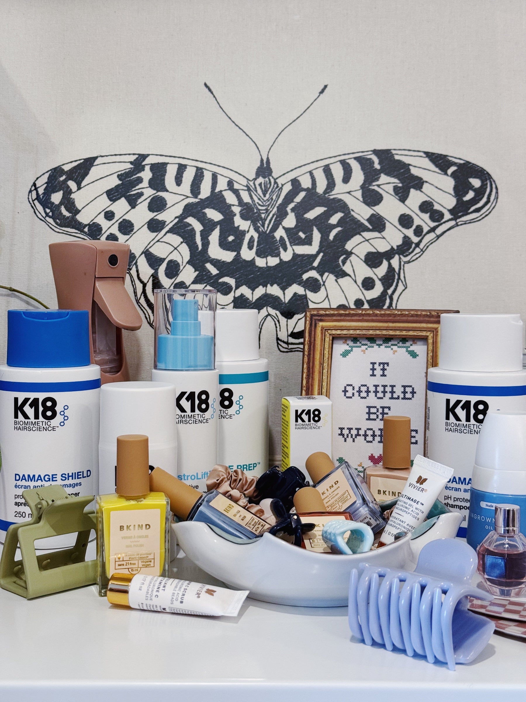 Collection of K18 hair care products with a butterfly illustration in the background.